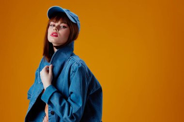 Cazibeli bir bayan kot giysisinin portresi. Poz veren sarı arka plan değiştirilmemiş.