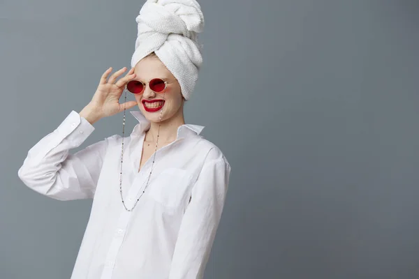 Λαμπερό γυναίκα κόκκινα γυαλιά ηλίου καλλυντικά με πετσέτα στο κεφάλι Γκρι φόντο — Φωτογραφία Αρχείου