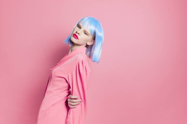 Mavi peruklu çekici bir kadın. Pembe elbiseli. Kırmızı dudaklı.