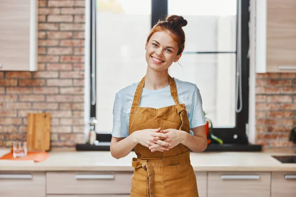 Jolie femme gestes avec ses mains dans un tablier brun cuisine intérieur Lifestyle — Photo