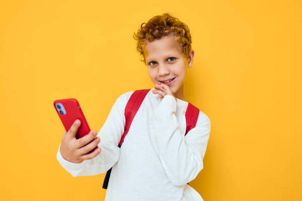 Cheerful young boy in white sweatshirt mobile cell phone red backpack Studio learning concept Stock Image
