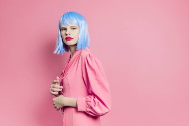 Modaya uygun bir kadın mavi peruk takıyor pembe arka plan
