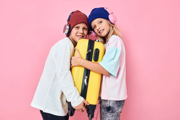 面白い男の子と女の子黄色のスーツケース付きヘッドフォン子供のライフスタイルコンセプト — ストック写真