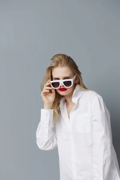 Beyaz gömlekli şık bir kadın güneş gözlüklü stüdyo modeli değiştirilmemiş. — Stok fotoğraf