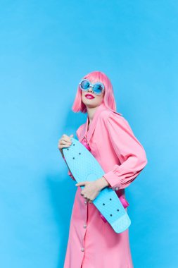 Güneş gözlüklü güzel kadın değiştirilmemiş pembe peruklu stüdyo modeli giyiyor.