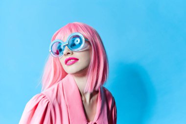 Mavi gözlüklü çekici kadın değiştirilmemiş pembe peruklu stüdyo modeli takıyor.