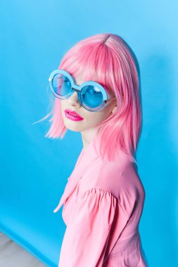 Pembe peruklu kadın moda gözlükleri takıyor.