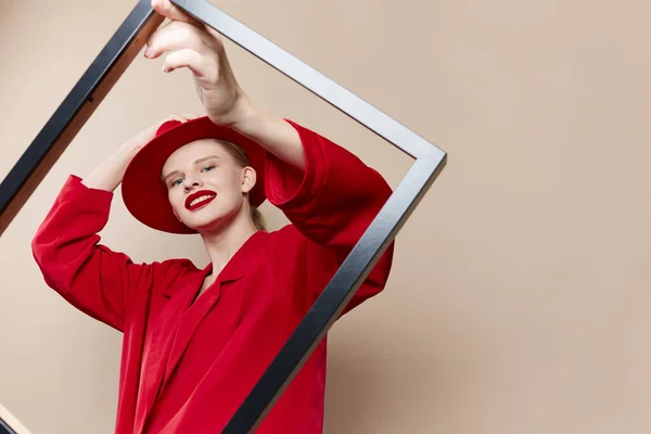 Mulher elegante com moldura de madeira posando vermelho terno fundo bege — Fotografia de Stock