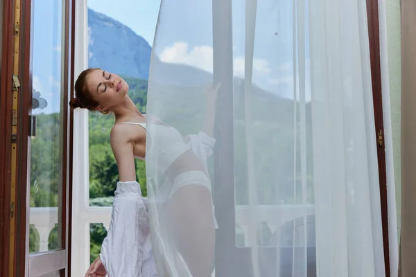 Fit woman in lingerie on the balcony beautiful view from the window unaltered — стоковое фото