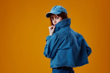 Pozitif genç kadın kot giysisi modayla poz veren sarı arka plan değiştirilmemiş.