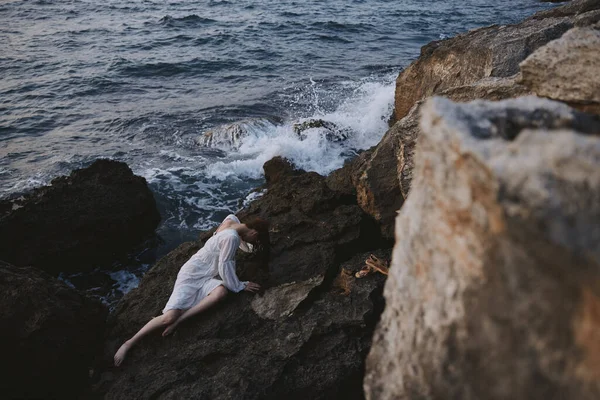 Woman lying on her back on a rocky seashore view from above — ストック写真