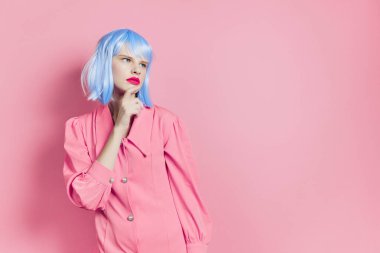 Mavi peruklu, pembe elbiseli, kırmızı dudaklı, göz kamaştırıcı bir kadın.