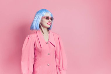 Güneş gözlüklü güzel kadın mavi peruk takıyor pembe arka plan