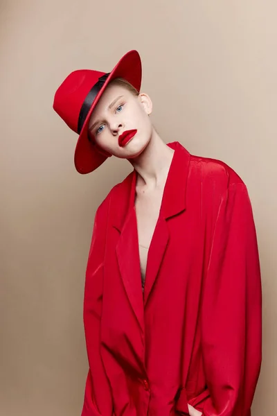 Mulher elegante casaco vermelho e chapéu lábios vermelhos moda fundo bege — Fotografia de Stock