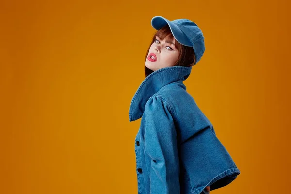 Portrait of a charming lady in a cap and denim jacket posing yellow background unaltered — Fotografia de Stock