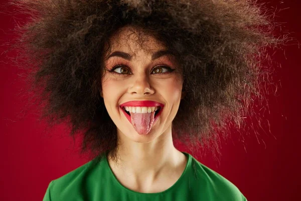 Pozitivní mladá žena s kudrnaté vlasy grimasa pózování emoce červené pozadí beze změny — Stock fotografie