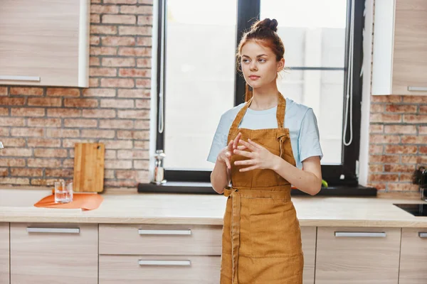 Belle femme dans un tablier dans la cuisine travaux ménagers inchangés — Photo