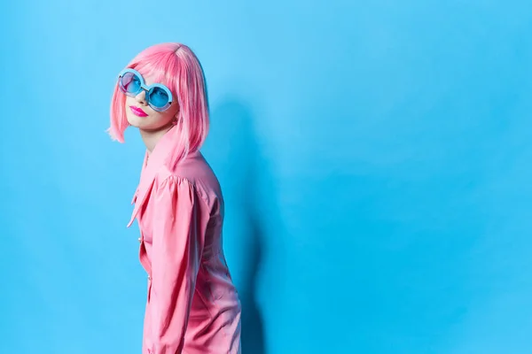 Glamorous woman in blue glasses wears a pink wig isolated background — стоковое фото