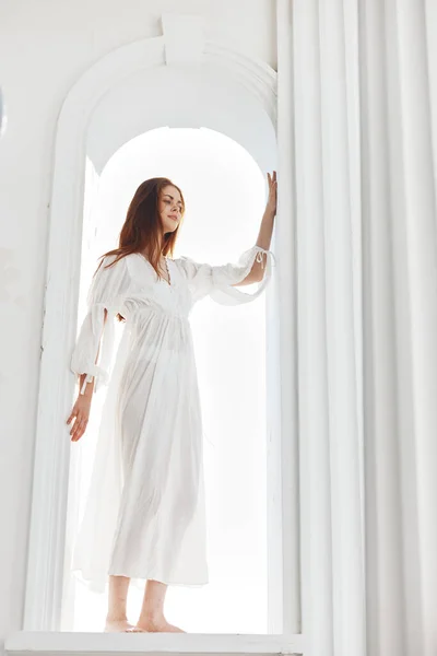Mulher em um vestido branco na abertura na forma de um arco posando — Fotografia de Stock