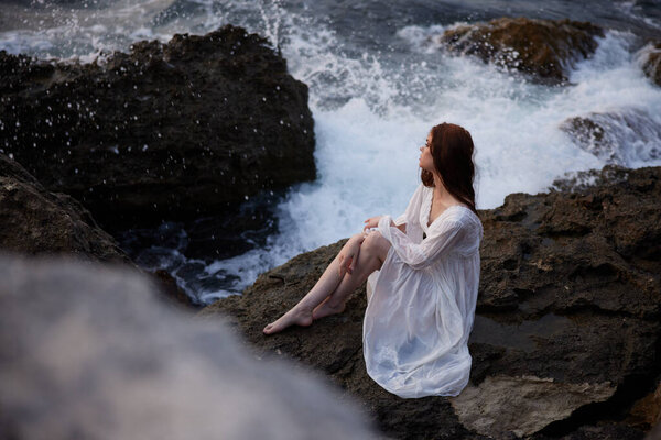 woman with wet hair in basik wedding dress sits on stones unaltered