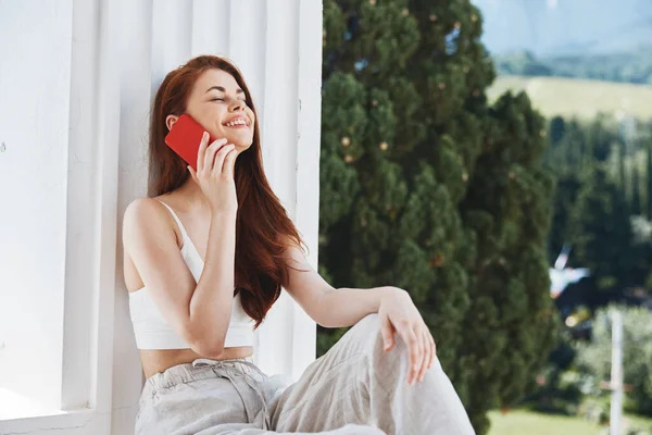 Portrait woman use the phone looks at the screen in a comfortable hotel an open view of the Mountain View — Fotografia de Stock