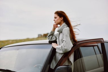 Arabanın yanında kırmızı saçlı bir kadının portresi. Kadın dinleniyor.