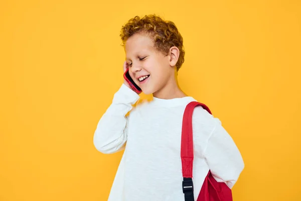 Tonårspojke med en röd ryggsäck samtal på telefonen isolerad bakgrund — Stockfoto