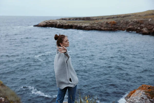 Woman in a gray sweater stands on a rocky shore nature Lifestyle — Stock Photo, Image
