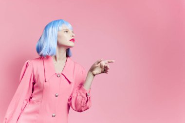 Mavi peruklu bir kadının portresi. Pembe elbise, kırmızı dudaklar, pembe arka plan.