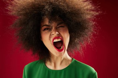 Pretty young female grimace afro hairstyle red lips fashion red background unaltered