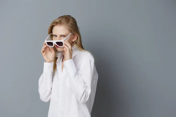 Beyaz gömlekli şık bir kadın güneş gözlüklü stüdyo modeli değiştirilmemiş. — Stok fotoğraf