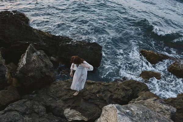 Красивая женщина с мокрыми волосами стоит на скалах у океана облачно — стоковое фото