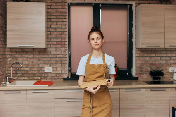 Una ama de casa en un delantal en la tabla de cortar de la cocina con el concepto del hogar del trabajo doméstico del cuchillo — Foto de Stock