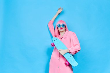 fashionable woman with skateboard in pink wig studio model unaltered