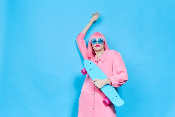 Fashionable woman with skateboard in pink wig studio model unaltered — Stockfoto