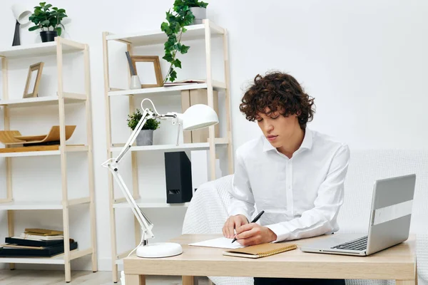 Curly guy on a white sofa in front of a laptop learning communication — ストック写真