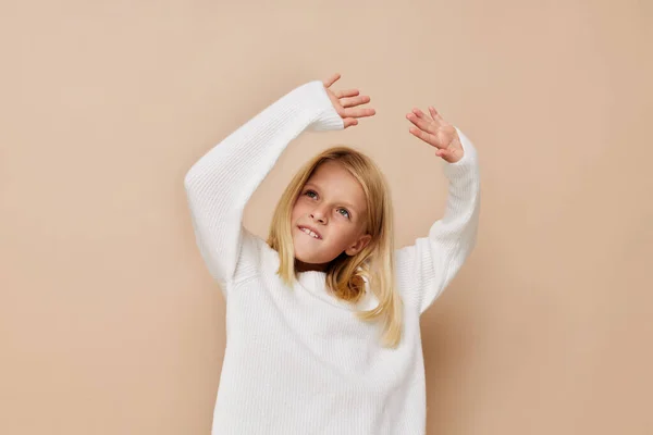 Happy cute girl in a sweater, grimaces on a beige background — 图库照片