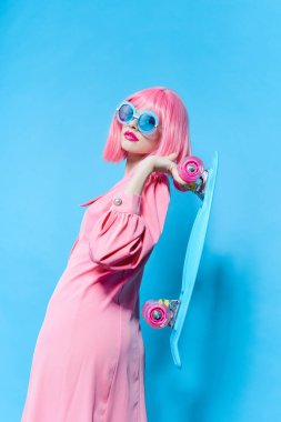 Güneş gözlüklü şık bir kadın değiştirilmemiş pembe peruklu bir stüdyo modeli takıyor.
