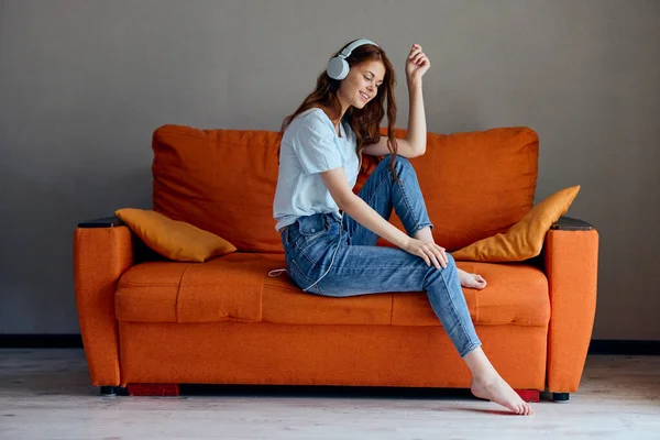 Beautiful woman headphone at home on the couch entertainment technologies — Fotografia de Stock