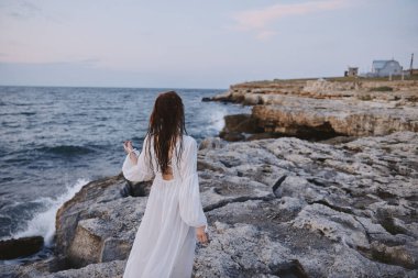 Freedom concept Beautiful girl standing on a rock on vacation