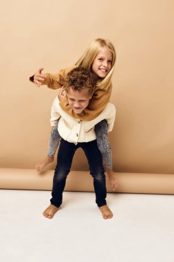 brother and sister together in sweaters fun casual wear beige background