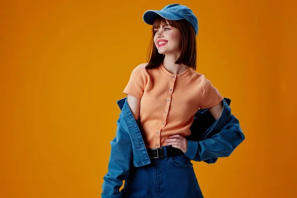 Досить молода жінка джинсовий одяг мода позує шапочку кольоровий фон незмінний — стокове фото