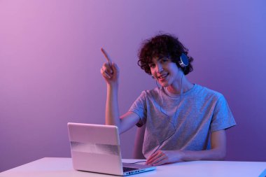 gamer in headphones in front of laptop entertainment violet background