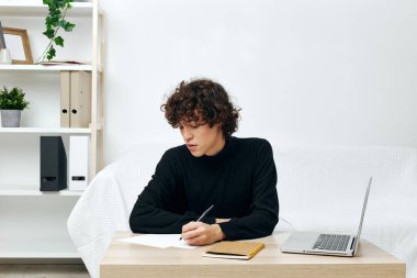 Masada oturan adam siyah süveter kursuyla iletişim kuruyor.