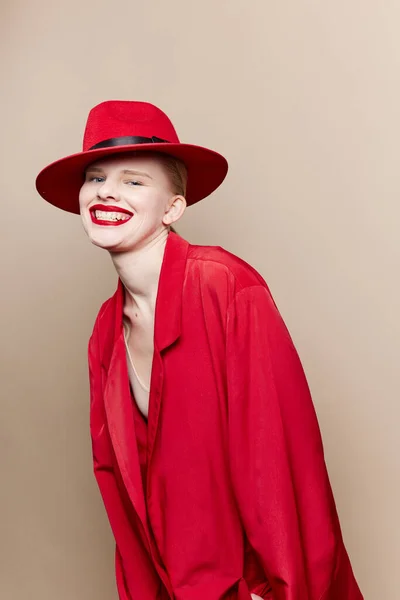Femme à la mode veste rouge et chapeau lèvres rouges mode fond beige — Photo
