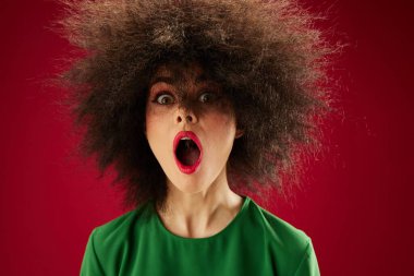 Pretty young female grimace afro hairstyle red lips fashion red background unaltered