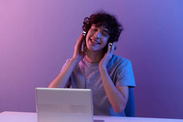Άνθρωπος κυβερνοχώρος παίζει με ακουστικά μπροστά από ένα laptop violet φόντο — Φωτογραφία Αρχείου