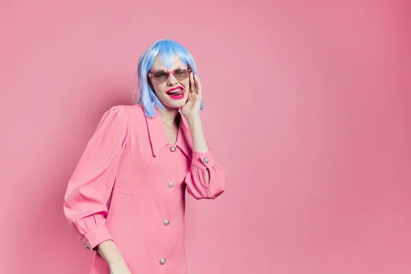 Модная женщина в солнечных очках носит синий парик макияж розовый фон — стоковое фото
