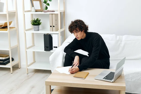 Curly guy on a white sofa in front of a laptop learning communication — ストック写真