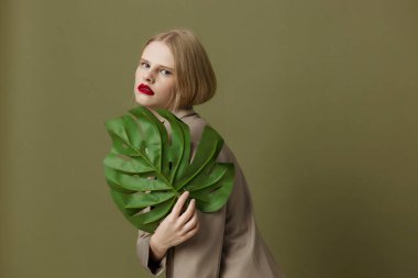 glamorous woman red lips holding  palm leaf  posing. High quality photo